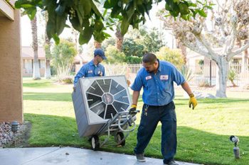 Technicians moving a central HVAC unit