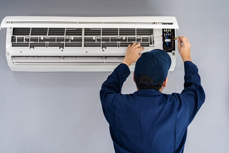 technician fixing a wall mounted HVAC unit